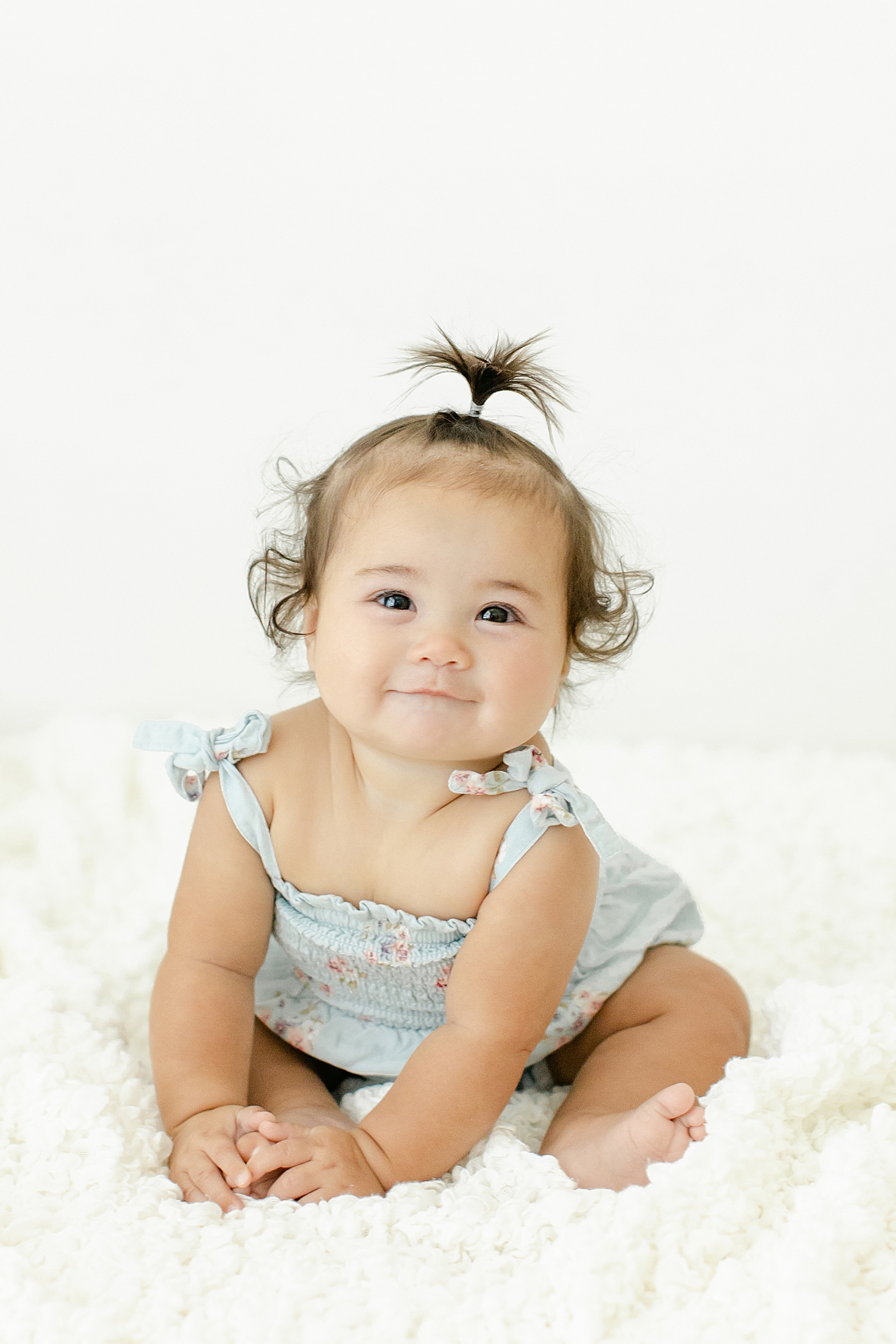 Baby girl in a blue jumper with tiny ponytail | Image by Chrissy Winchester Photography