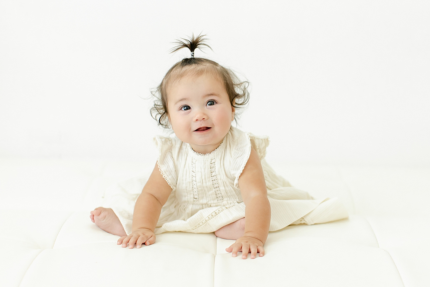 Baby girl in a white dress during her Six Month Studio Session | Image by Chrissy Winchester Photography