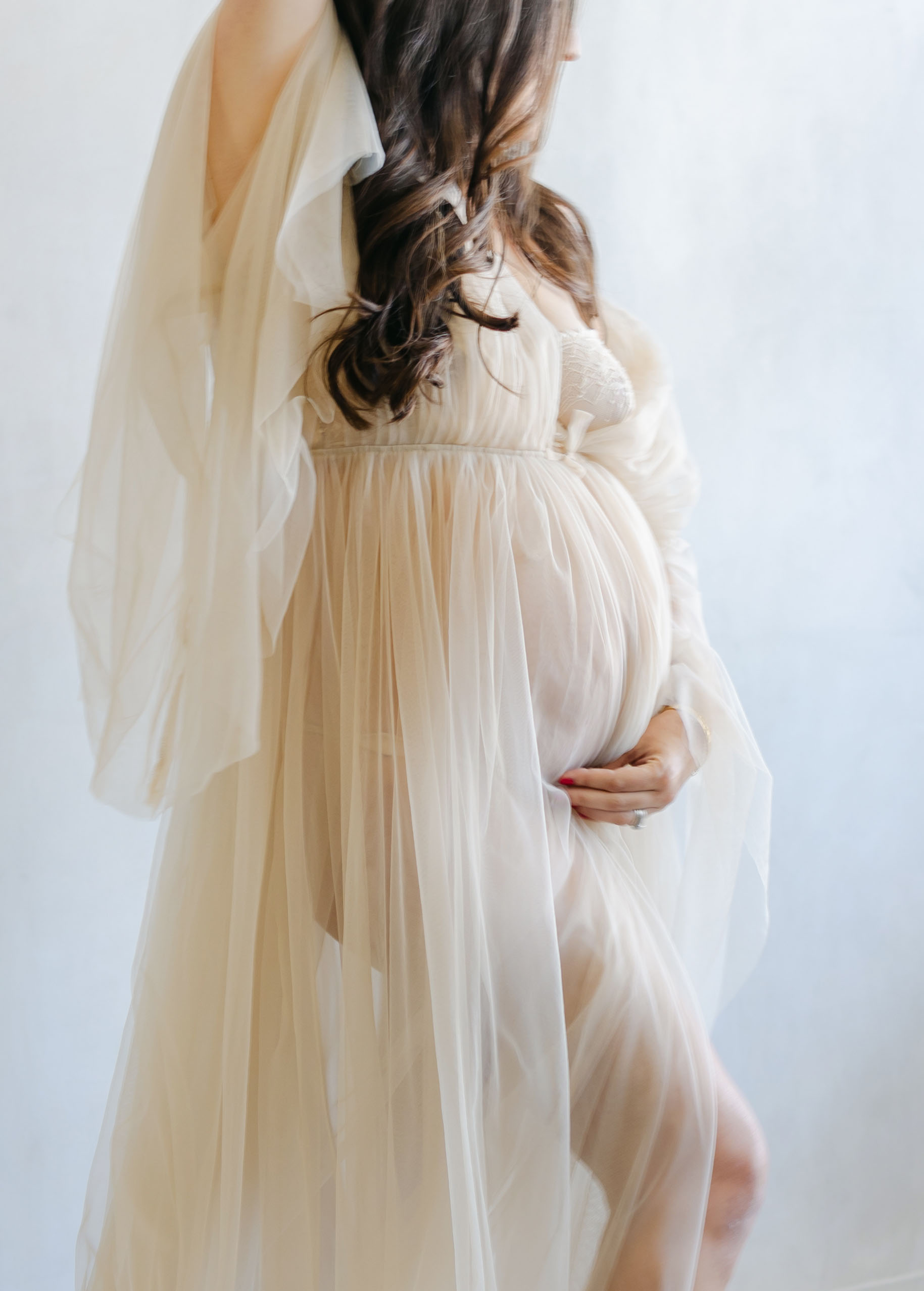 beautiful brunette expectant mom holding belly in cream tulle dress