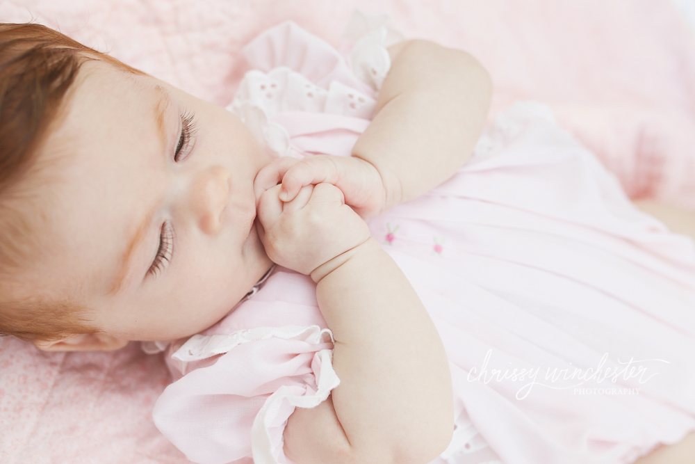 Baby girl in pink eating hands