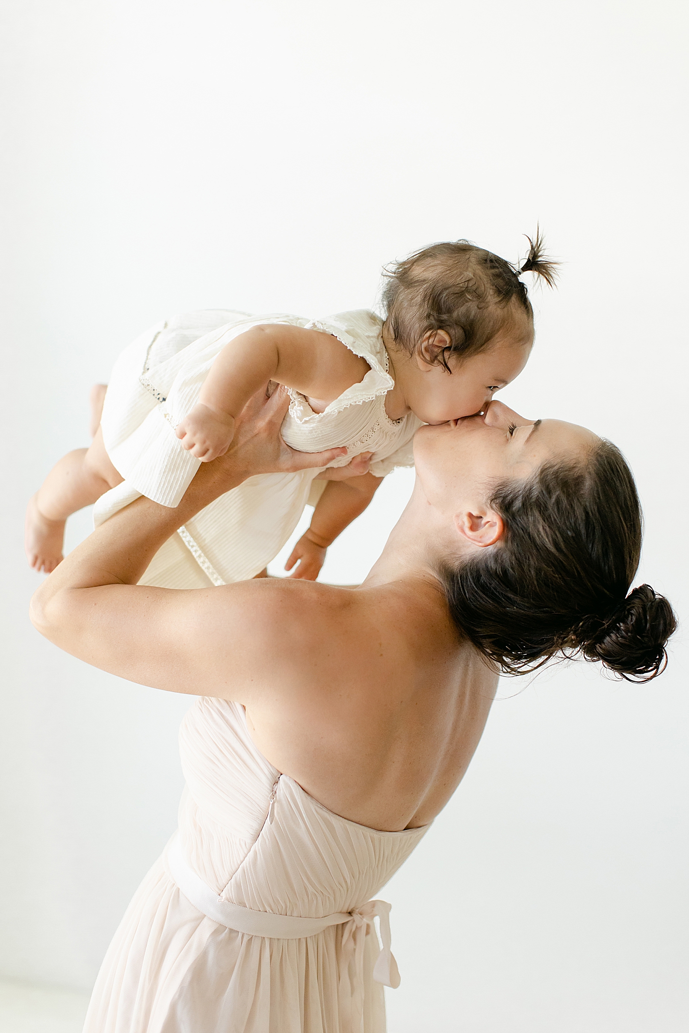 Mom playing airplane with her baby girl in matching dresses | Image by Chrissy Winchester Photography