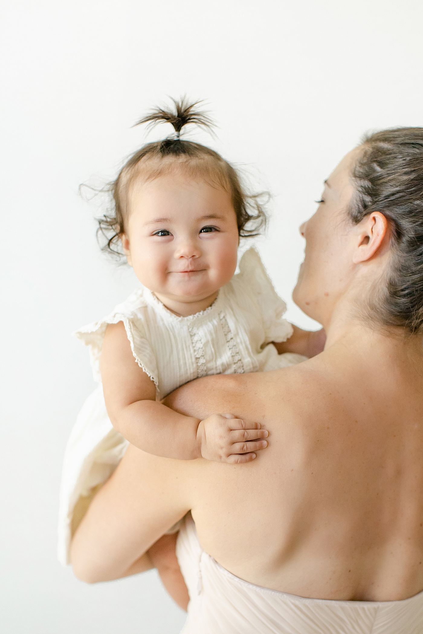Baby girl held by mom smiling | Image by Chrissy Winchester Photography