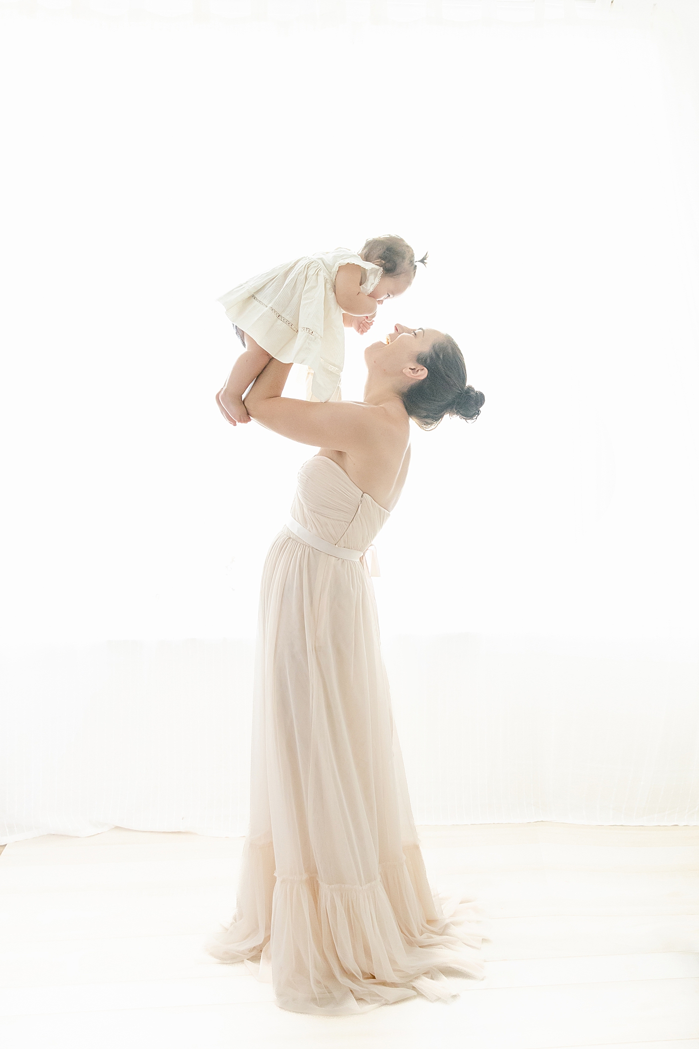 Mom playing airplane with her baby girl | Image by Chrissy Winchester Photography