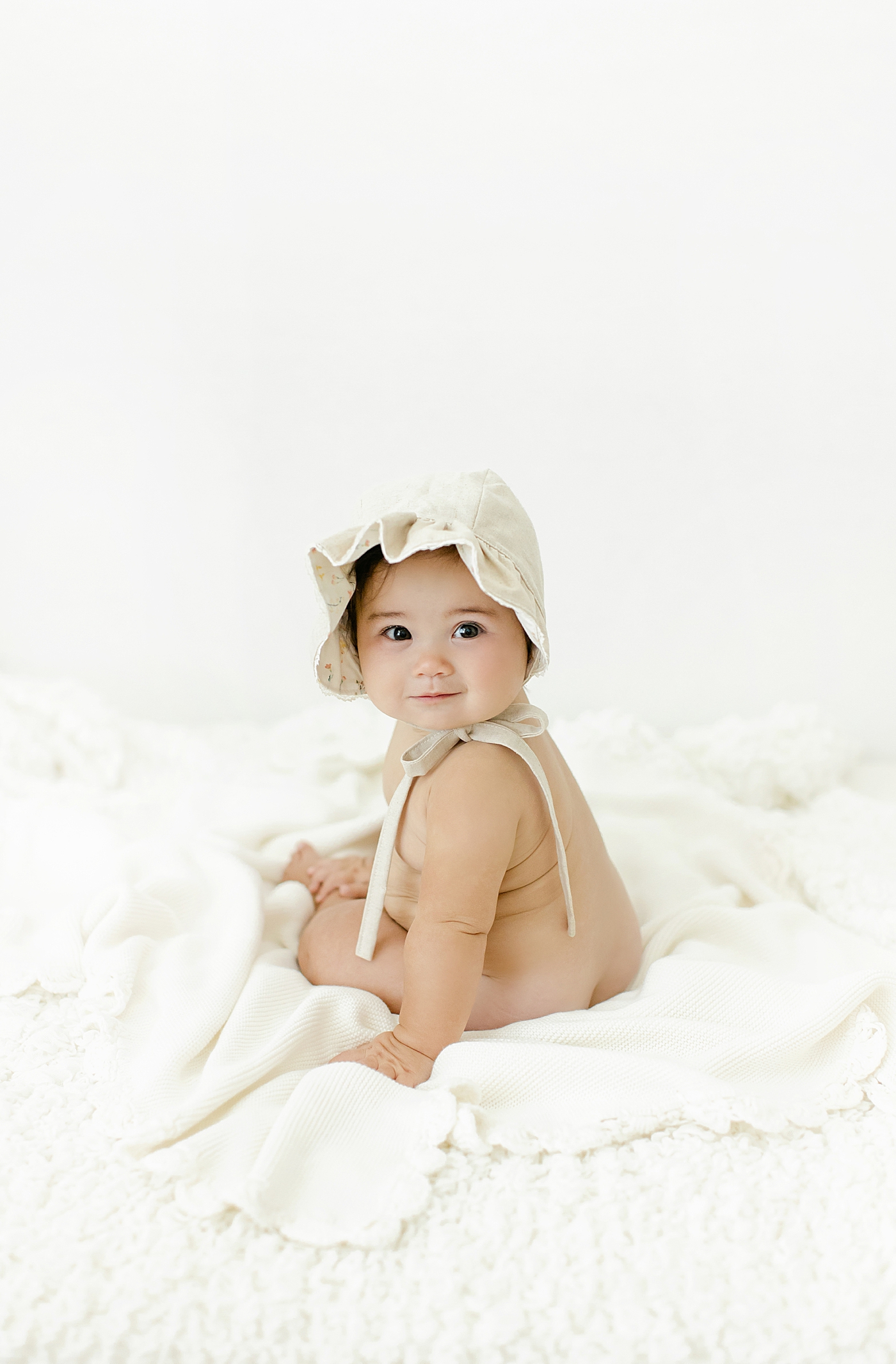 Smiling baby girl wearing a bonnet during her Six Month Studio Session | Image by Chrissy Winchester Photography