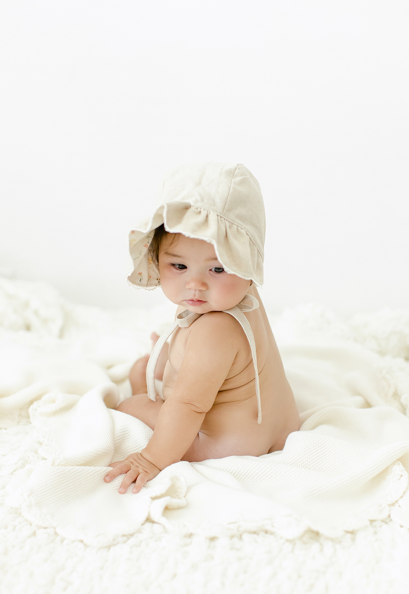 Baby girl in a bonnet looking over her shoulder | Image by Chrissy Winchester Photography