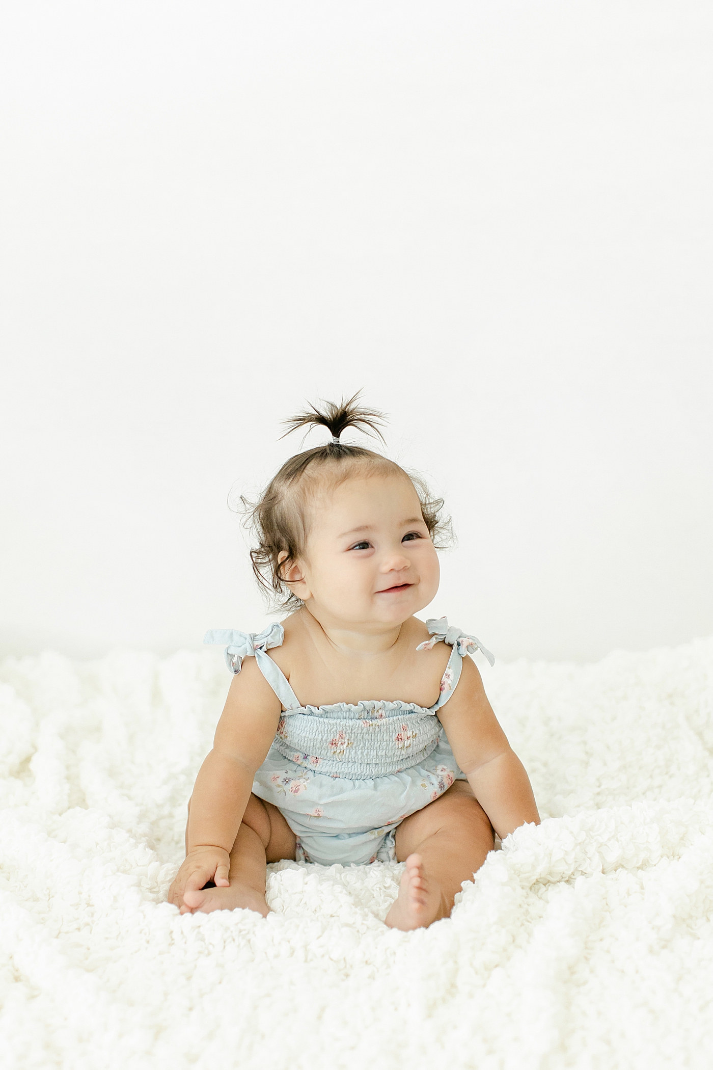 Smiling baby girl in a blue jumper during her Six Month Studio Session | Image by Chrissy Winchester Photography