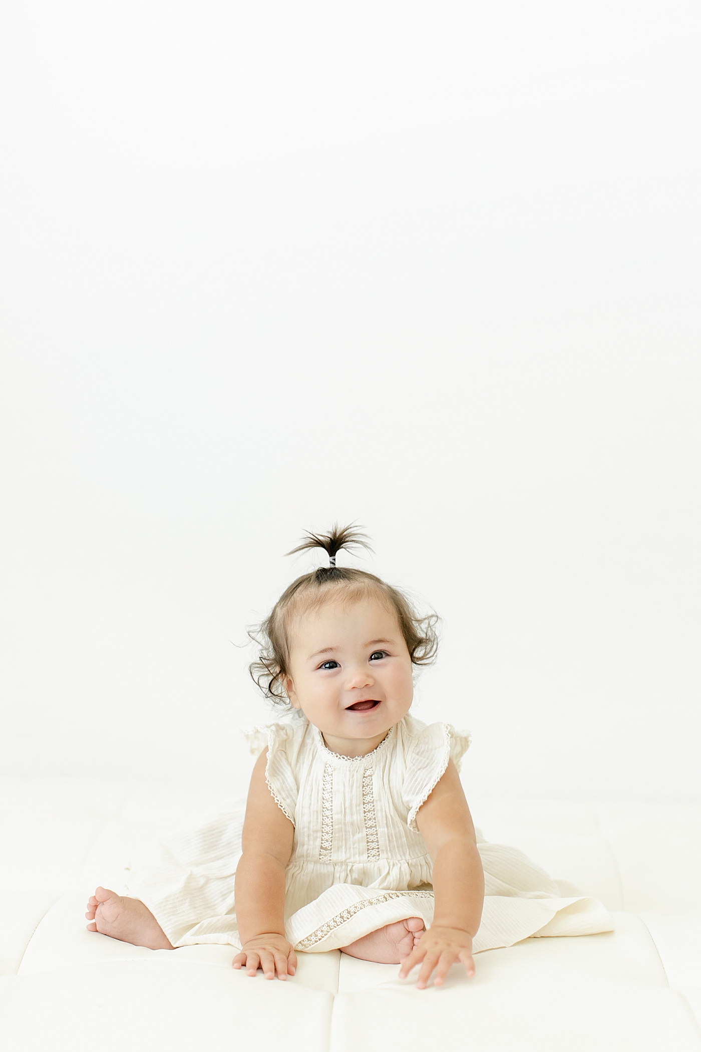 Baby girl with a ponytail in a cream dress | Image by Chrissy Winchester Photography