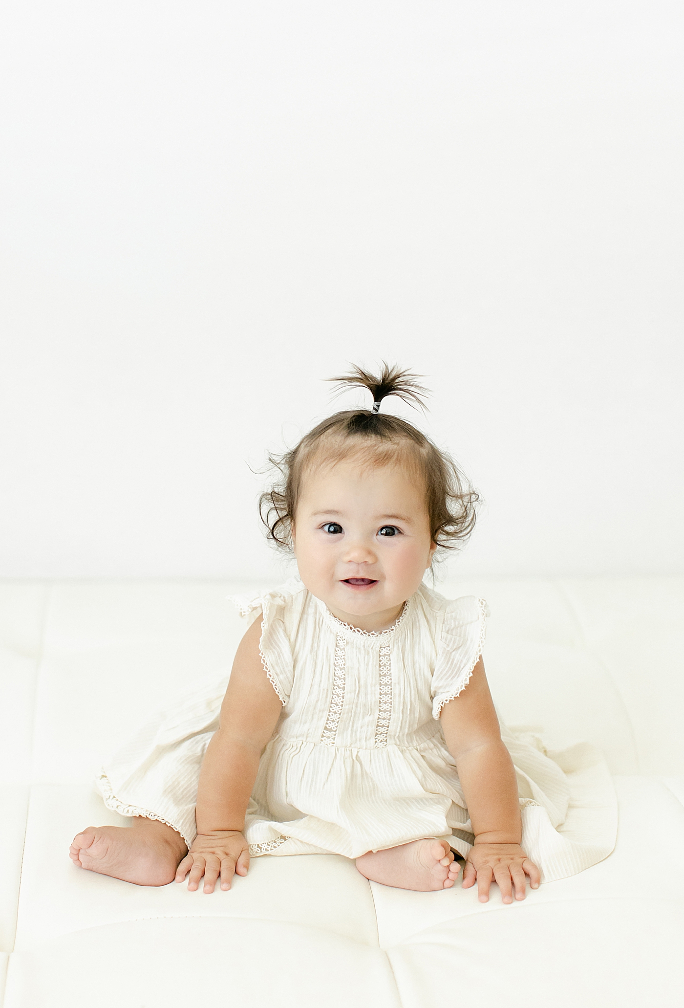 Baby girl in a white dress during her Six Month Studio Session | Image by Chrissy Winchester Photography