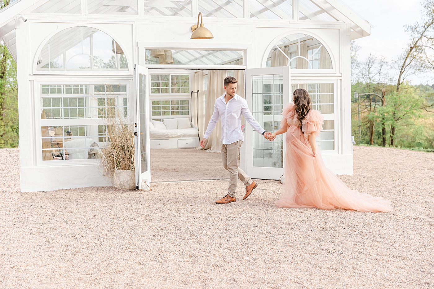 Couple holding hands walking in front of a greenhouse | Image by Chrissy Winchester