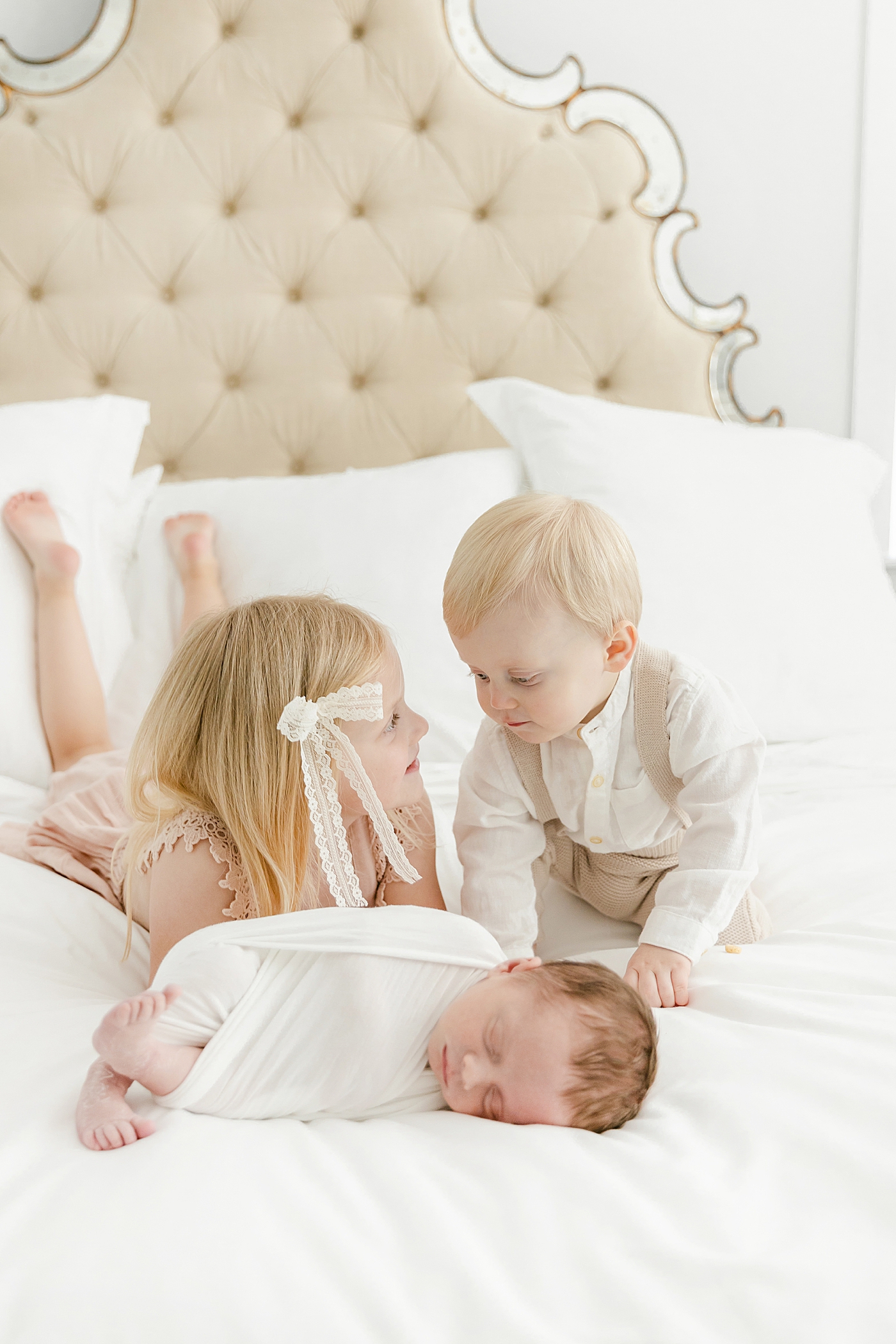 Big brother and sister snuggling with their newborn baby brother | Image by Sana Ahmed Photography